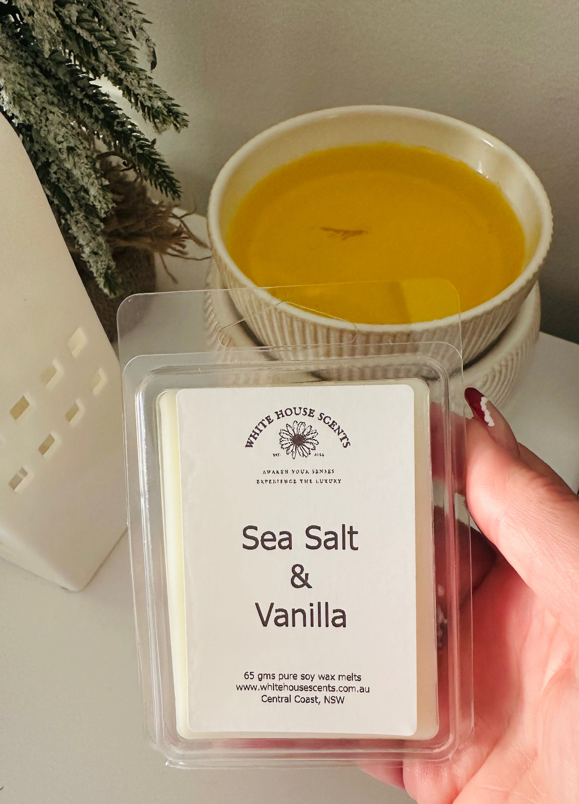 White House Scents Sea Salt & Vanilla wax melt with a bowl of yellow liquid in the background.