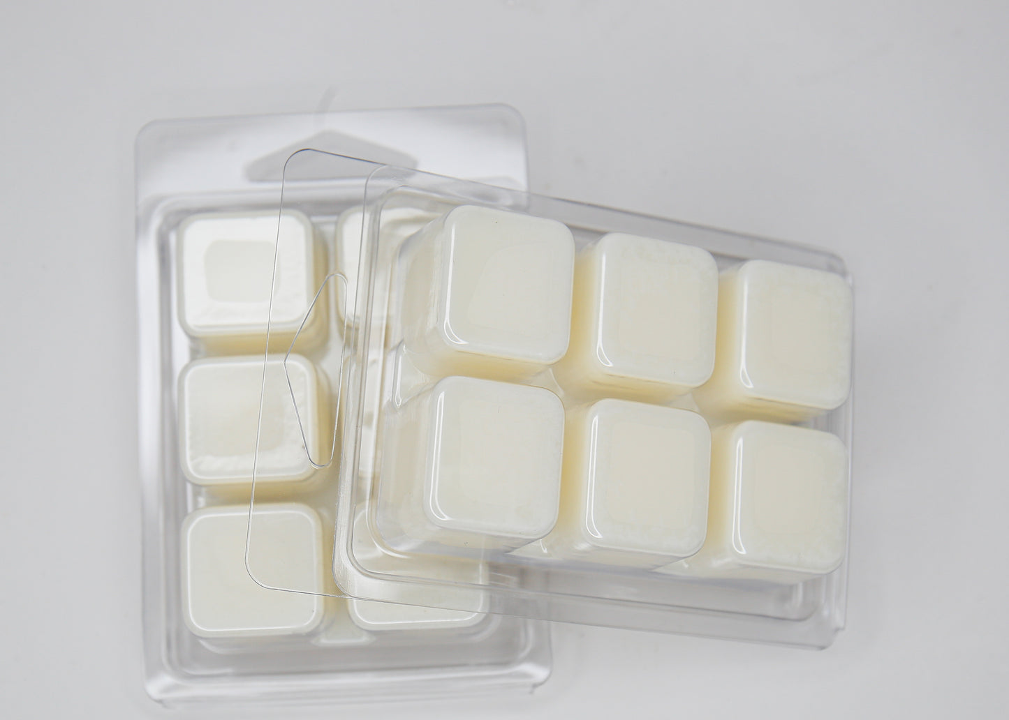 Pack of wax melts in a clear plastic container on a light gray background