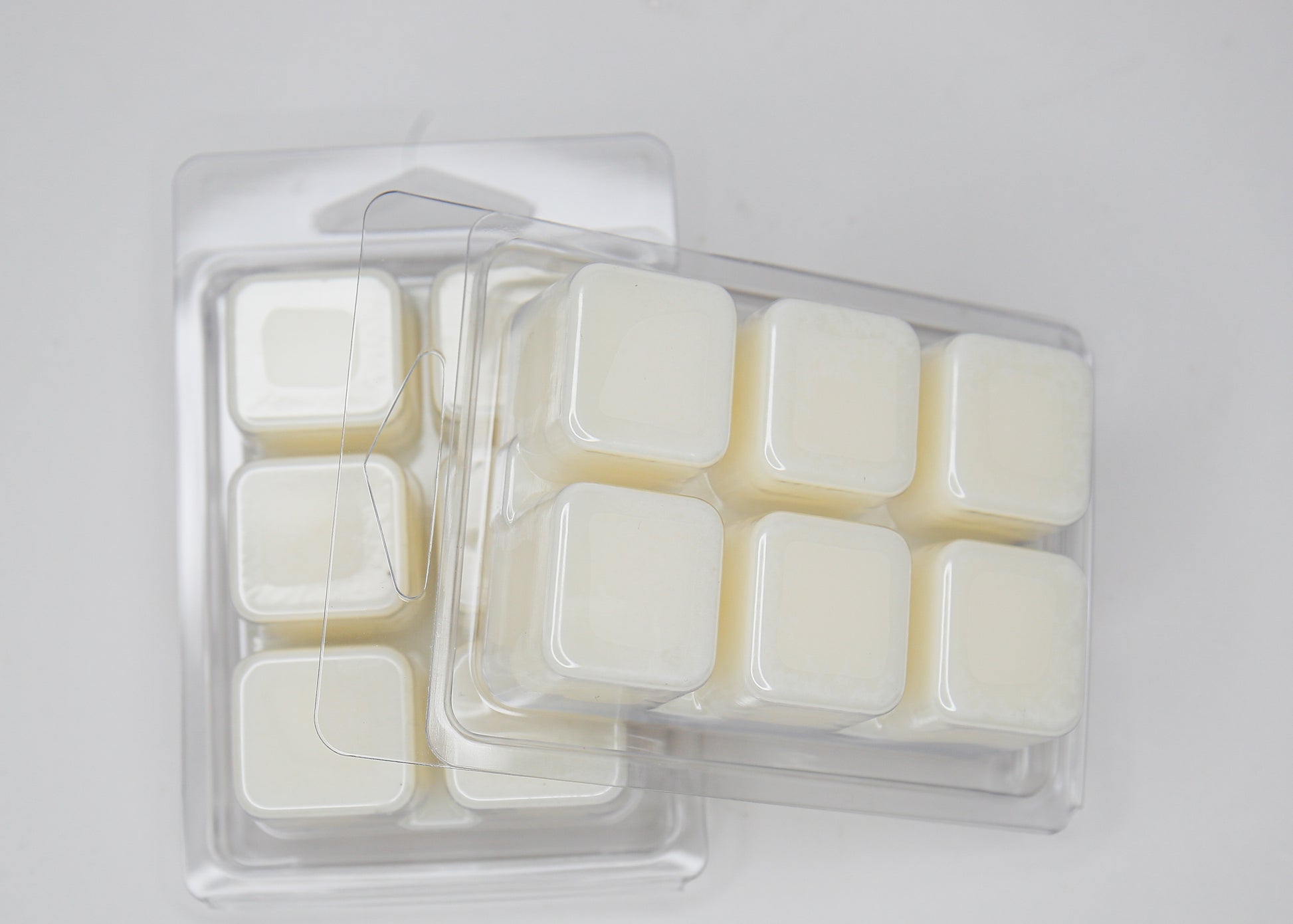 Pack of wax melts in a clear plastic container on a light gray background